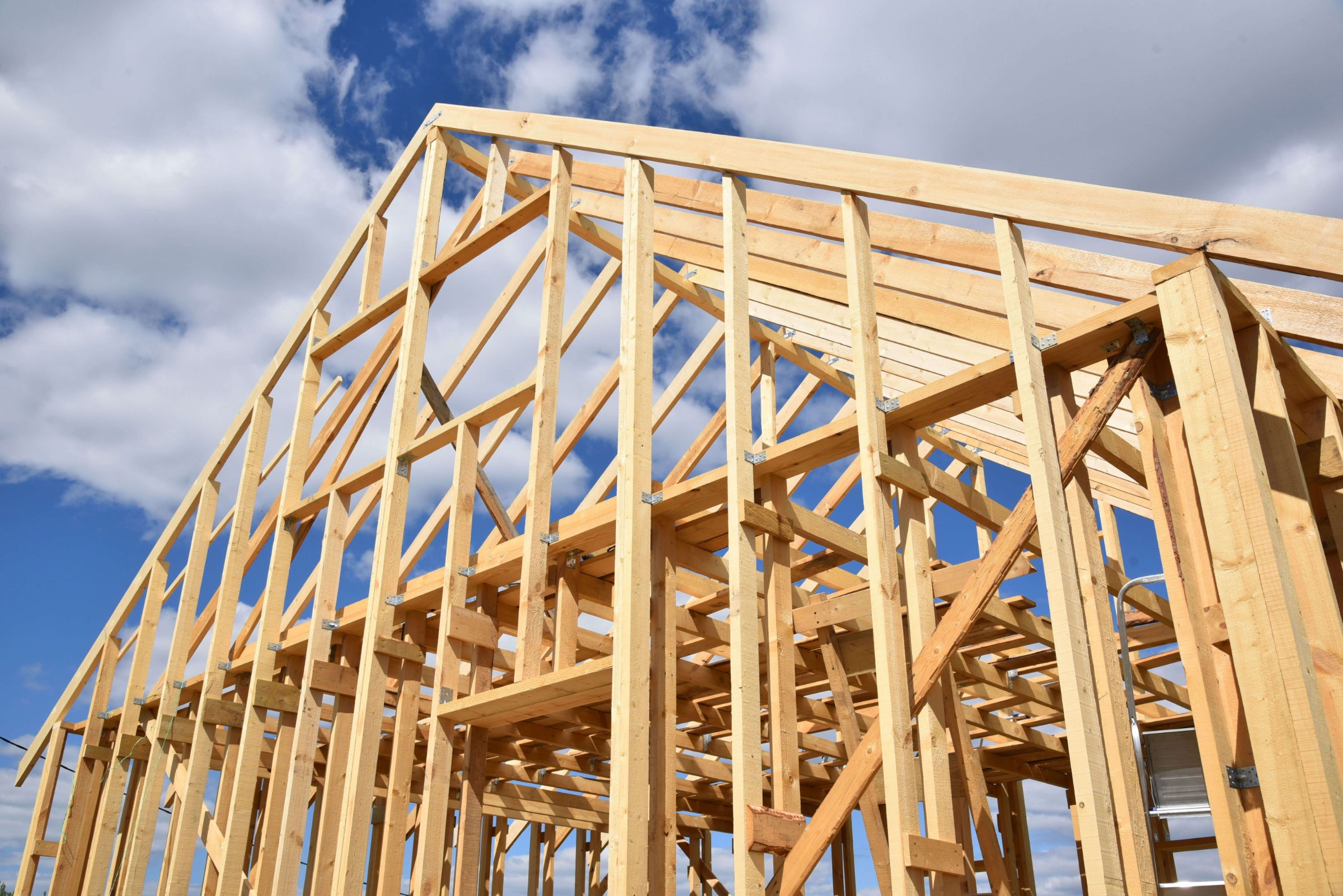 Timber-framed home under construction against a blue sky